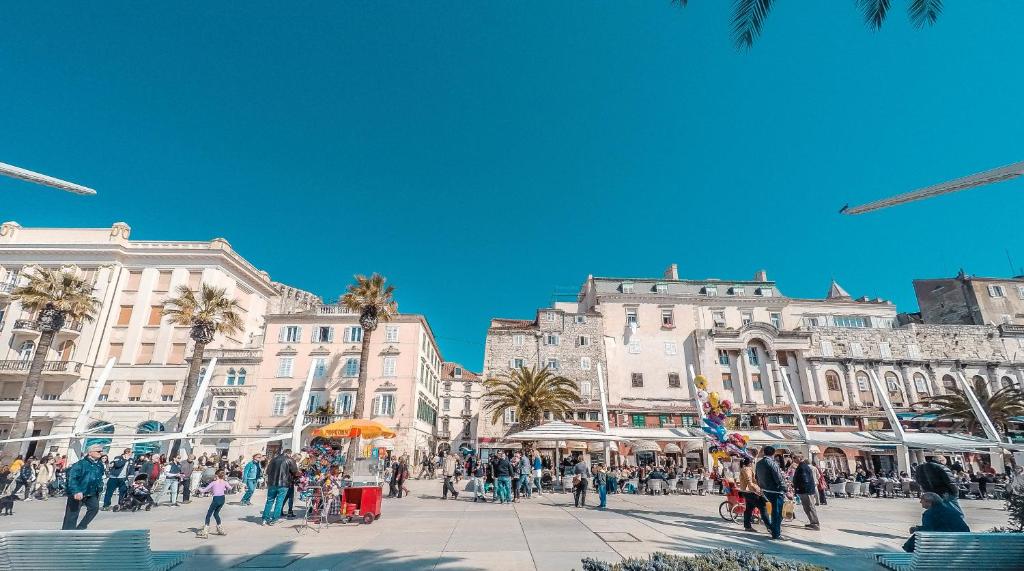 una folla di persone che camminano per una strada di fronte agli edifici di Hotel Kastel 1700 a Spalato (Split)