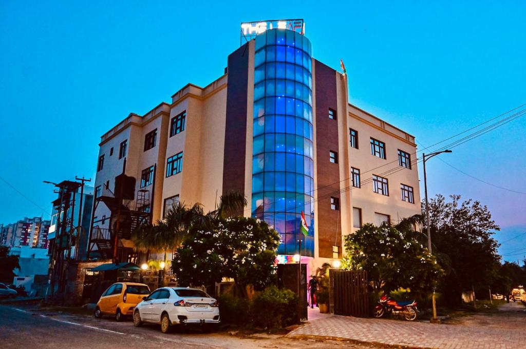 un edificio alto con coches estacionados frente a él en Hotel The Leaf - Gomti Nagar Lucknow, en Lucknow