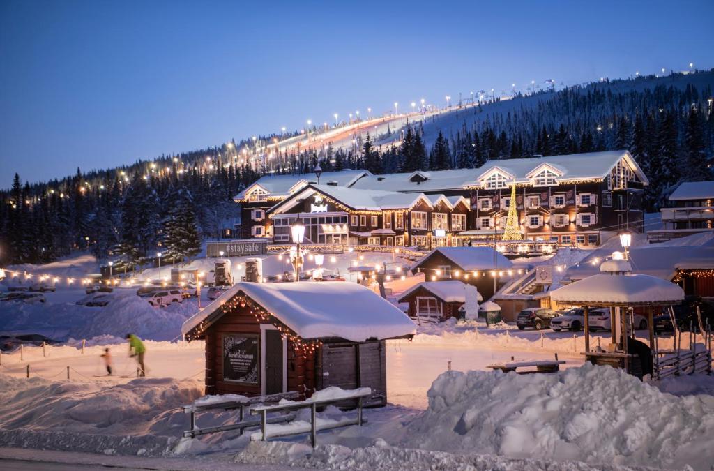 un resort en la nieve por la noche con luces en Hotel Bügelhof en Lindvallen