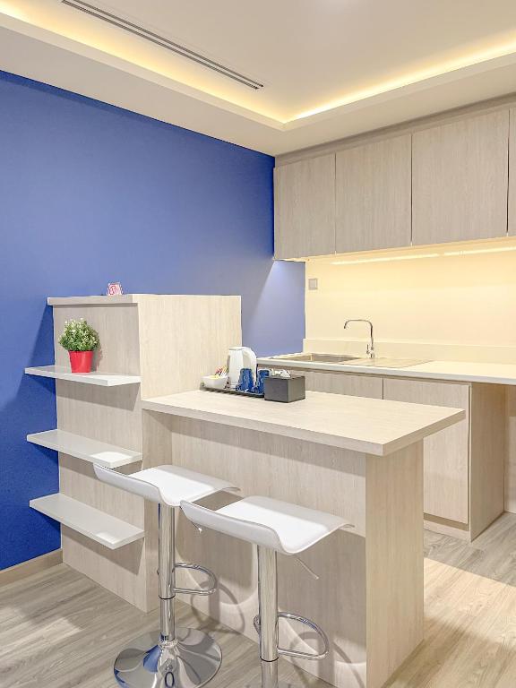 A kitchenette with a sink, overhead cabinets, counter seating, and two bar stools.