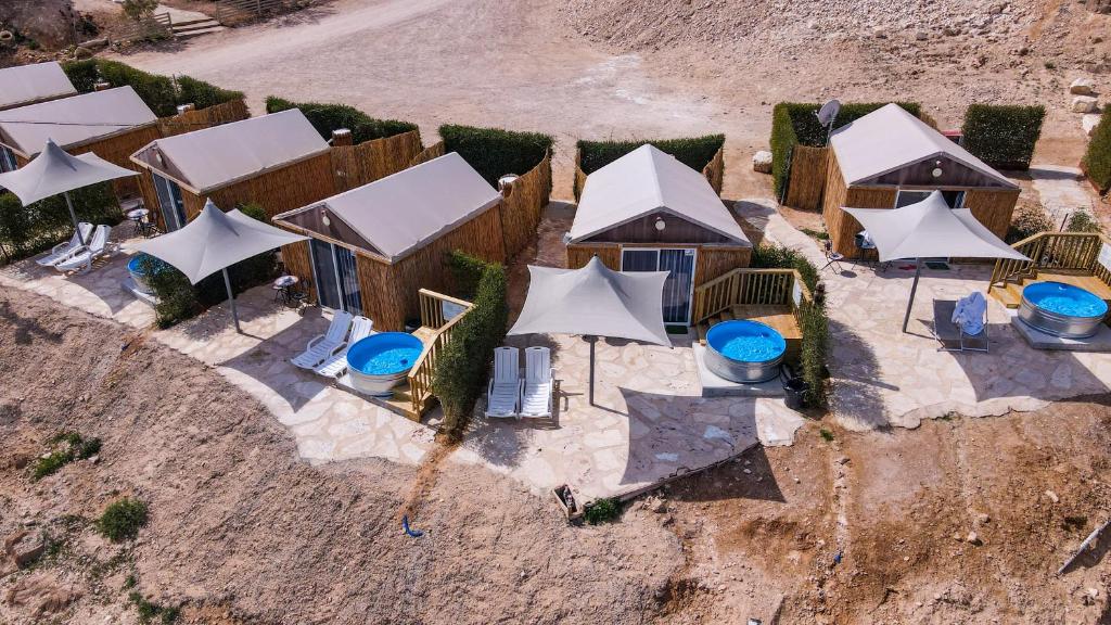 an aerial view of a resort with white umbrellas at Tenty on the Cliff - Metzoke Dragot in Metsoke Dragot