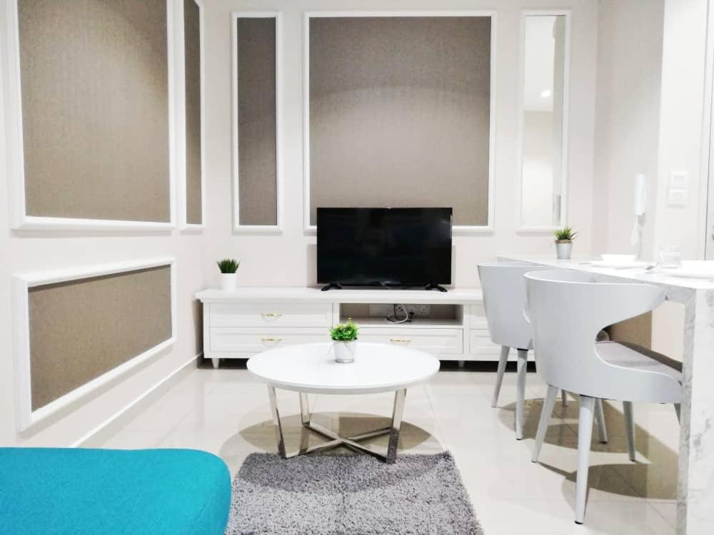 uma sala de estar branca com uma televisão, uma mesa e cadeiras em Luxury Blue Paris Suite # I-City # Free Wifi + Free Parking [1r1b] em Shah Alam