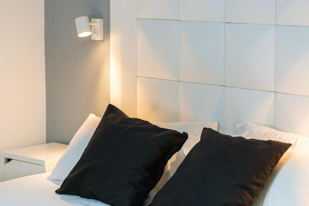 a white bed with two black pillows on it at Carpe Diem Apartment in Bali