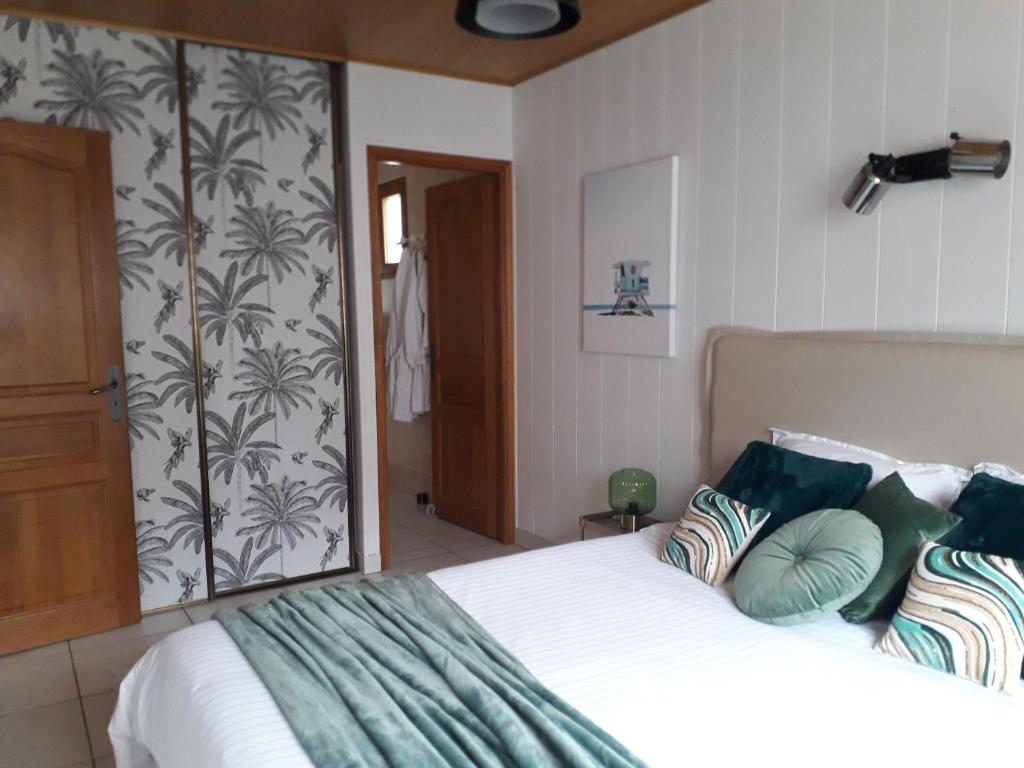 - une chambre avec un grand lit et des oreillers verts dans l'établissement Belle de Dune, à La Baule