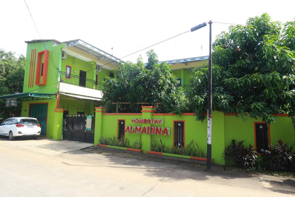 a green building with a car parked in front of it at Homestay Almadina Syariah in Jepara