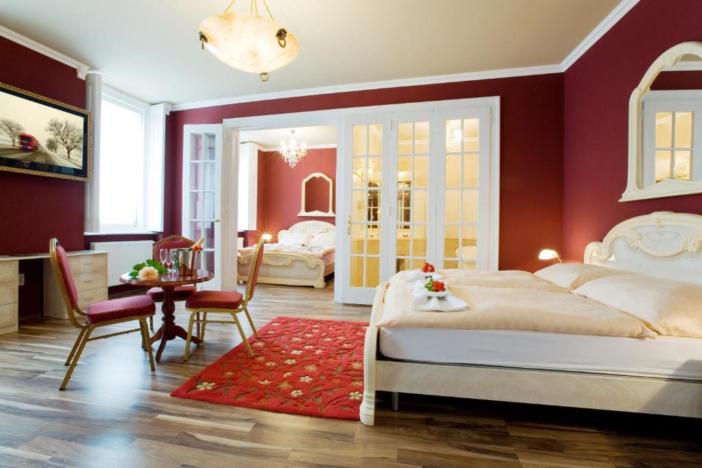 Schlafzimmer mit roten Wänden, einem Bett und einem Tisch in der Unterkunft Hotel Bow Garden in Komárno
