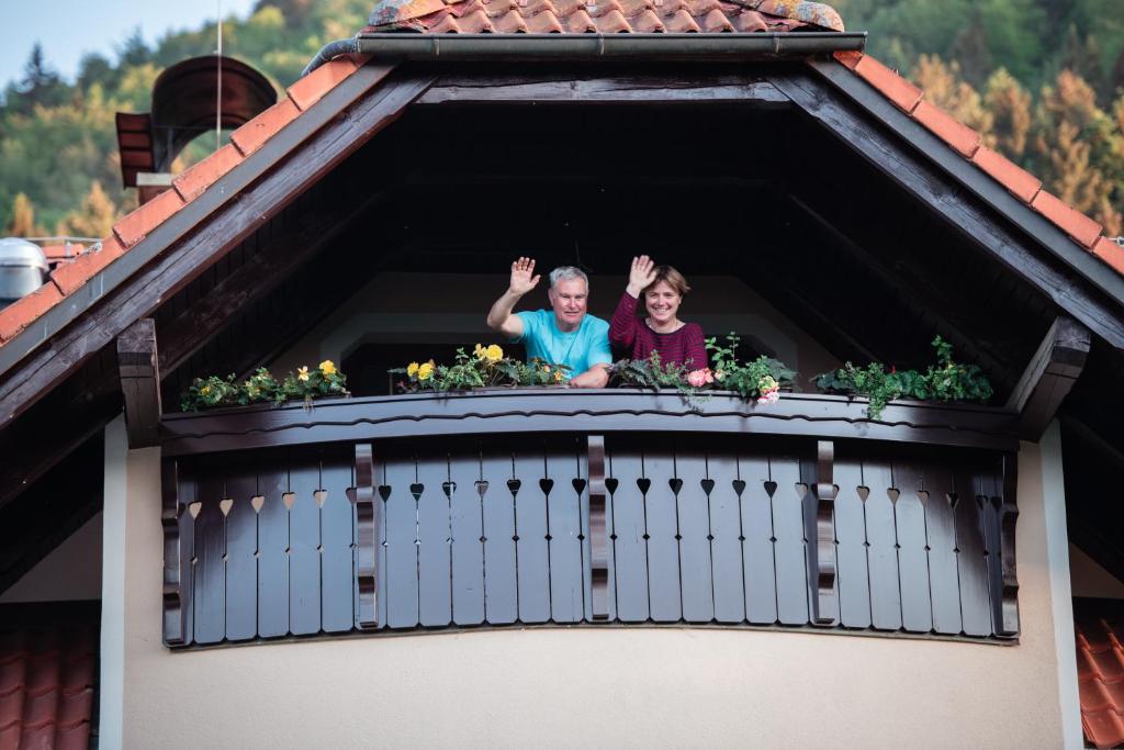 duas pessoas acenando de uma janela de uma casa em Eco Tourist Farm Ravnjak em Slovenj Gradec