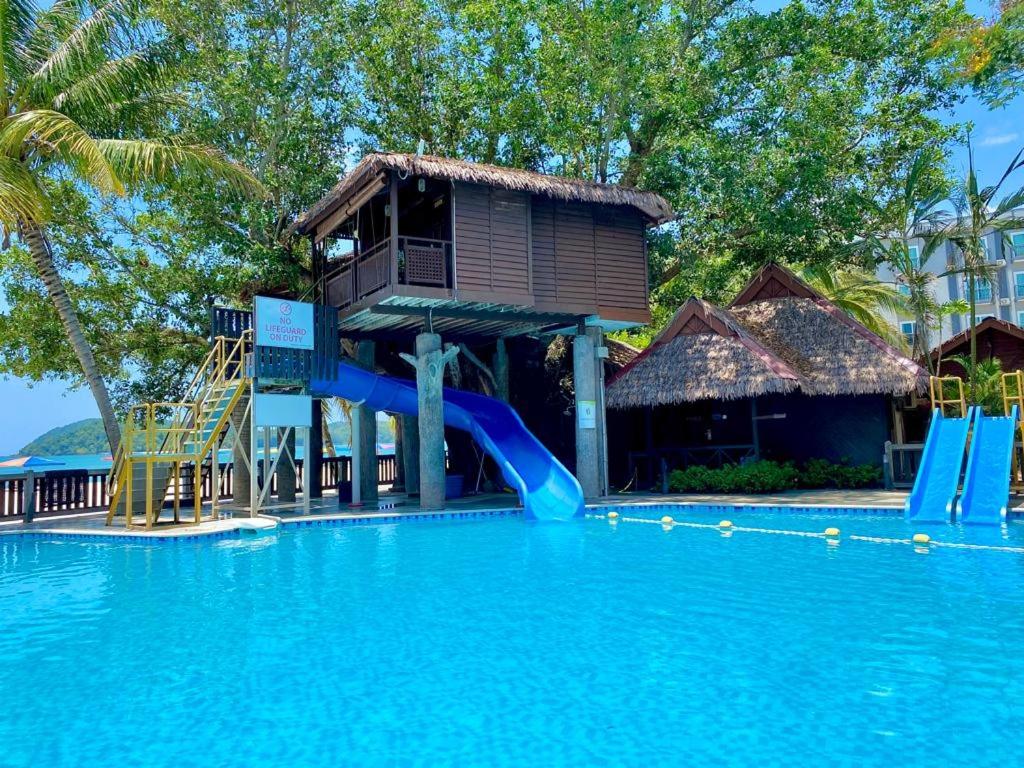 a resort with a slide in the middle of a swimming pool at Malibest Resort in Pantai Cenang