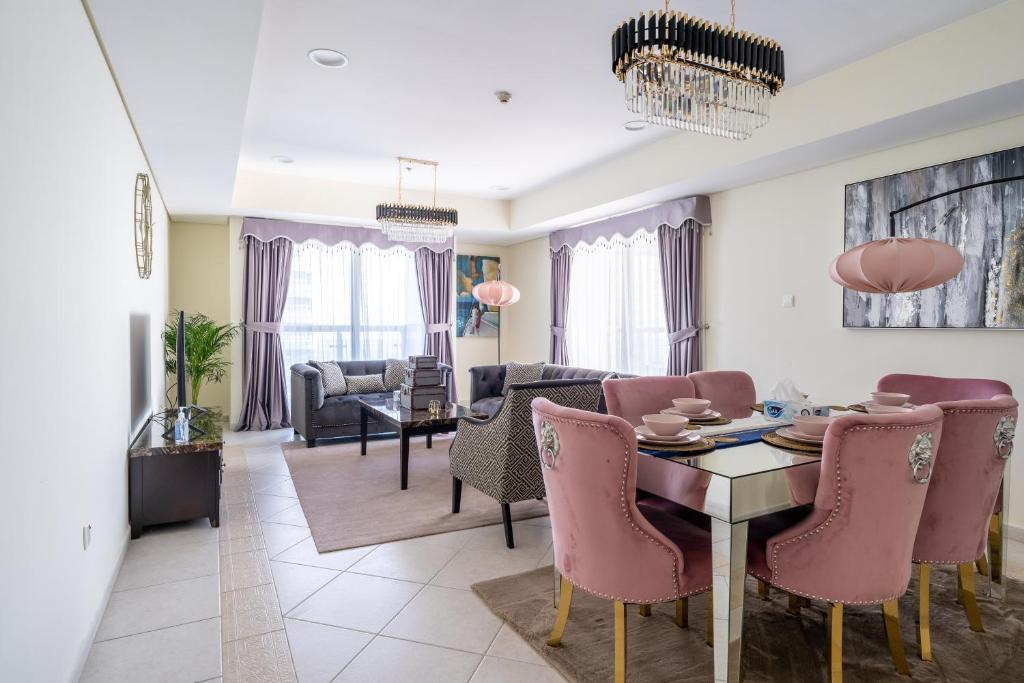 a living room with a dining table and pink chairs at Veer Apartments in Dubai