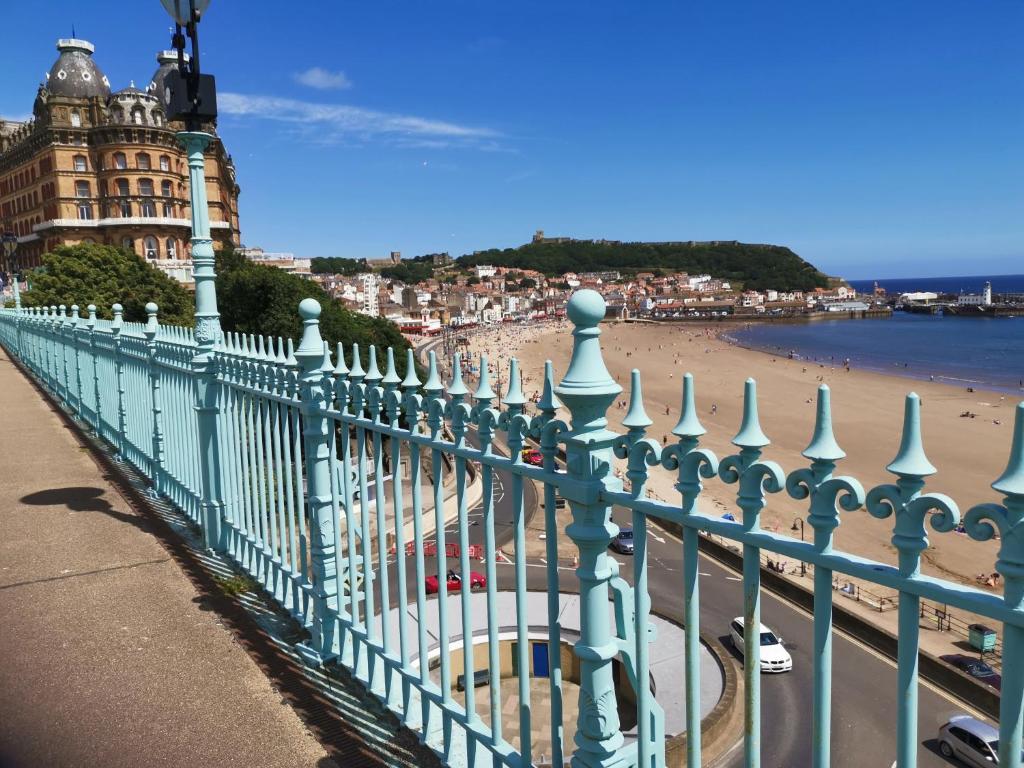 a fence next to a beach with a building at Scarborough, South Cliff Seaside Garden Apt in Scarborough