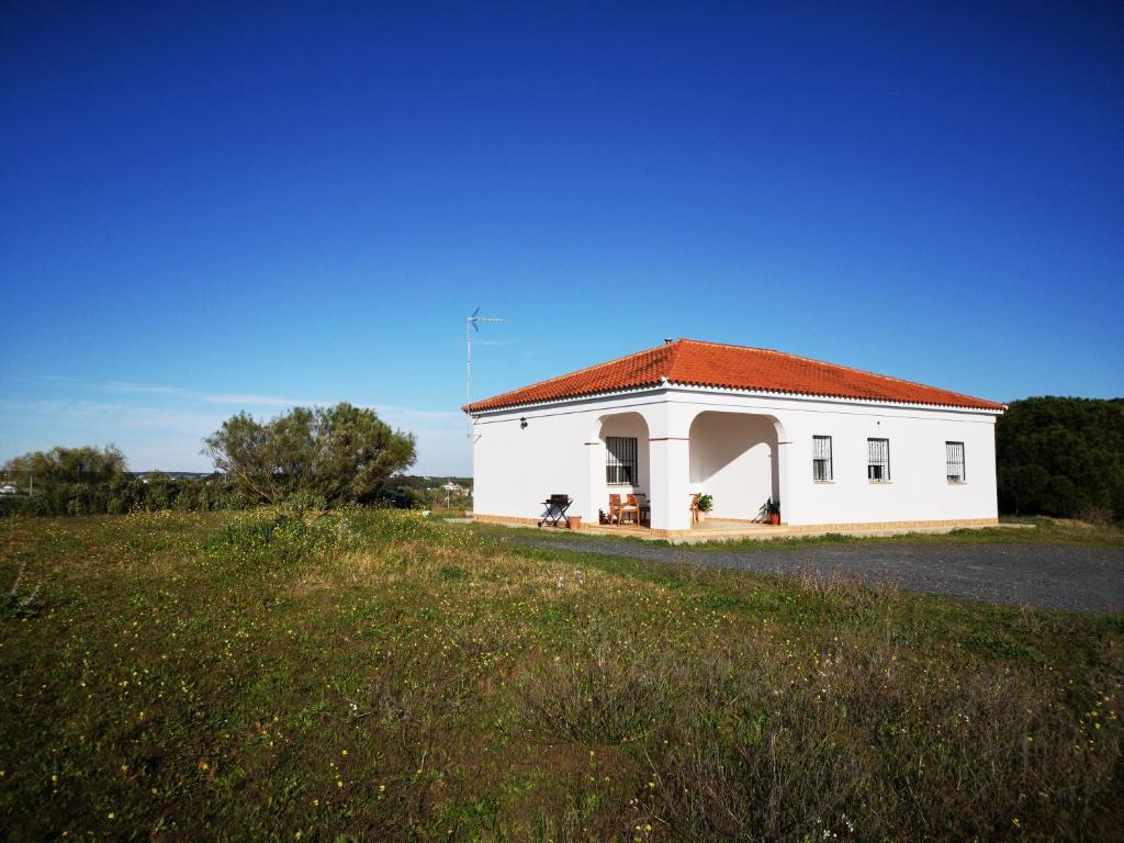 een wit gebouw met een rood dak op een veld bij Casa Rural Cerca de la Playa El Rompido in El Rompido