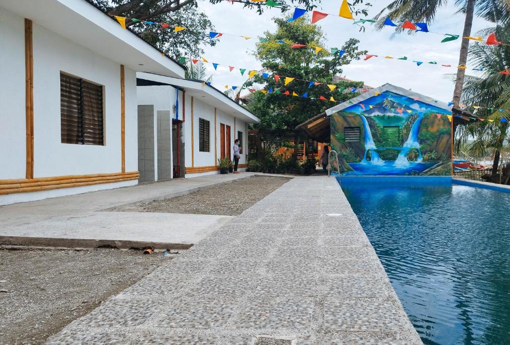 uma piscina ao lado de uma casa com bandeiras e um edifício em Casa Nena Hotel & Resort Iloilo by RedDoorz em Iloilo City