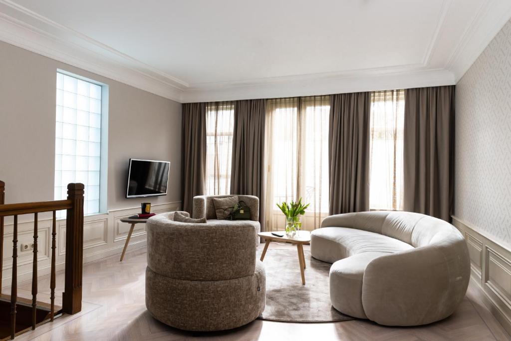 ein Wohnzimmer mit einem Sofa, Stühlen und einem TV in der Unterkunft Amsterdam Canal Suites in Amsterdam