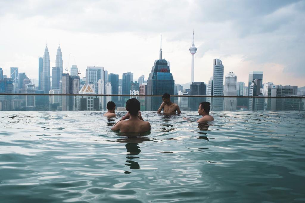 a group of people in a infinity pool with a city skyline at The Common Room @ Regalia in Kuala Lumpur