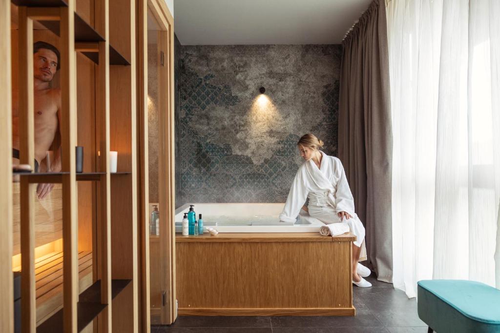 une femme assise dans une baignoire dans une salle de bains dans l'établissement RELAIS CASCINA ERA, à Sandigliano