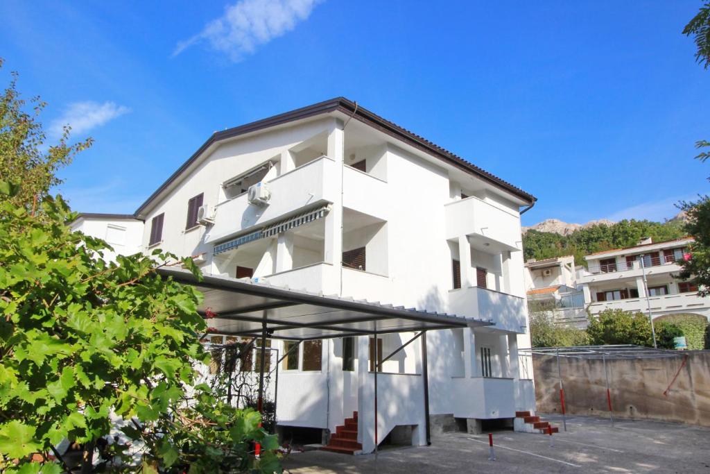 a white house with a black roof at Apartment Sersic in Baška