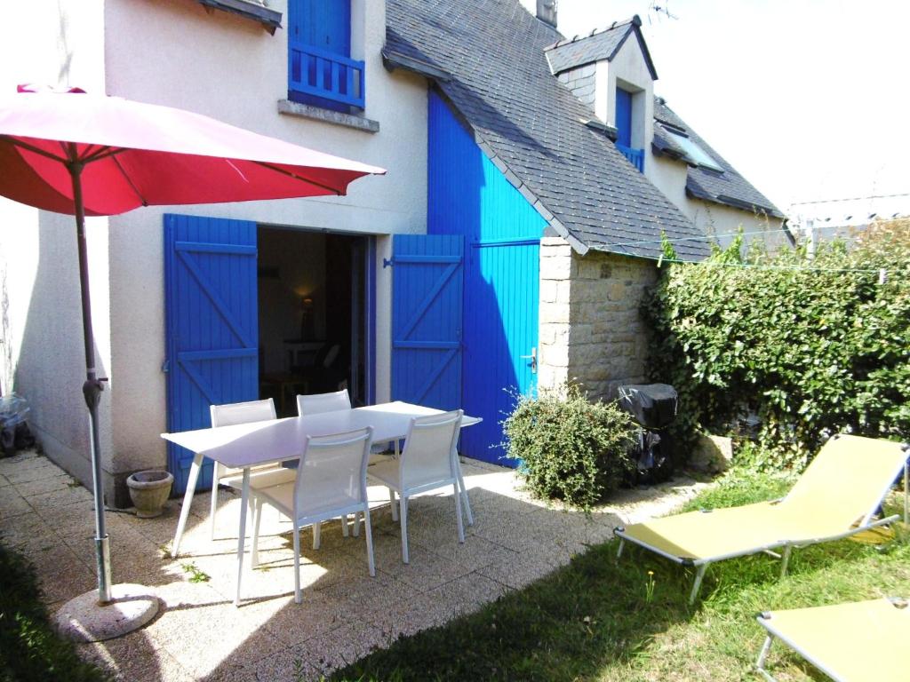 une table, des chaises et un parasol rouge devant une maison dans l'établissement Maisonnette 3 pièces 5 personnes à 200 m de la plage - MIKAEL, à Sarzeau