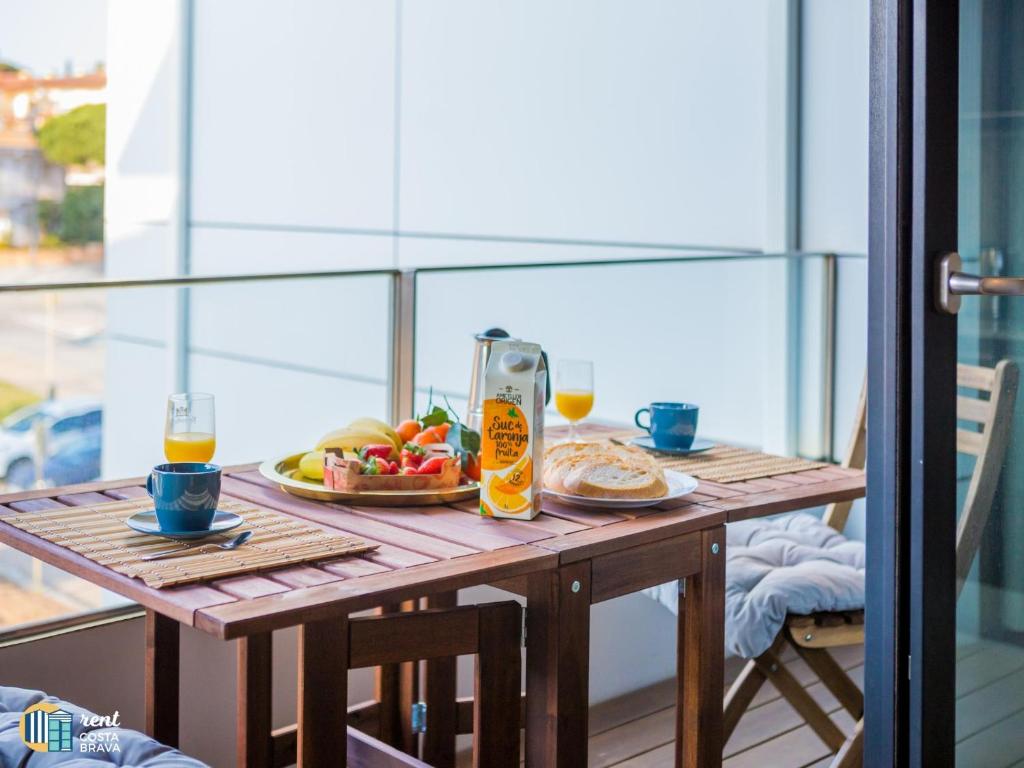uma mesa de madeira com um prato de comida e sumo de laranja em Apto Diana em Platja d'Aro