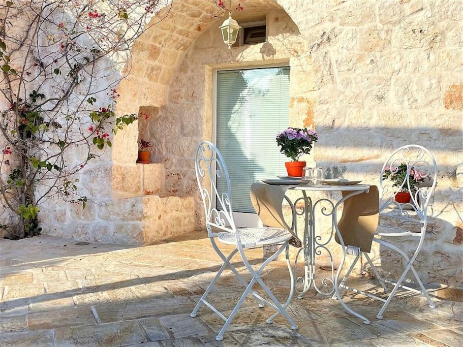une table et des chaises assises devant un bâtiment dans l'établissement Oasi del Trullo, à Ostuni