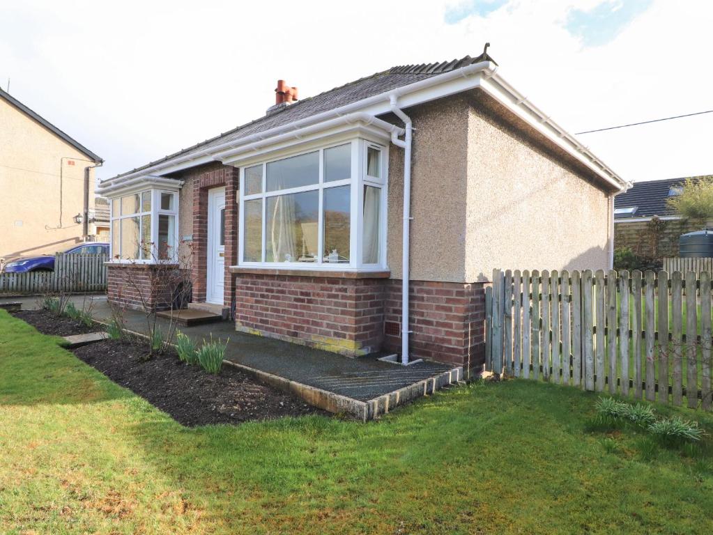 una casa de ladrillo con una valla en un patio en Eusebank en Pooley Bridge