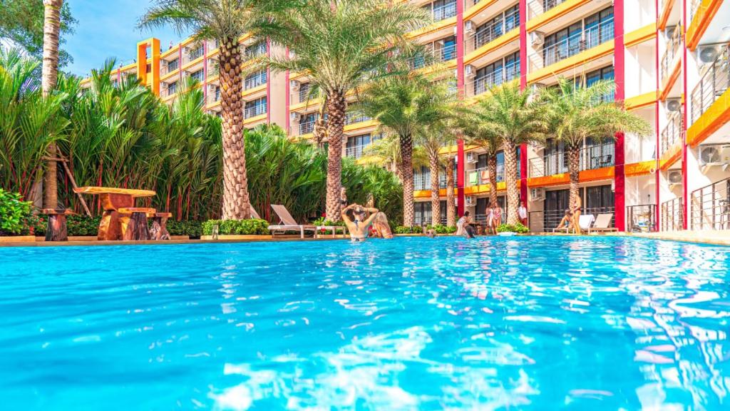 a swimming pool in front of a building with palm trees at Mai Khao Beach Condotel - family condo in 600 meters to beach in Ban Bo Sai Klang
