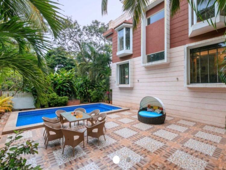 une terrasse avec une table, des chaises et une piscine dans l'établissement 4BHK Luxury Villa with Private Pool Near Candolim, à Marmagao