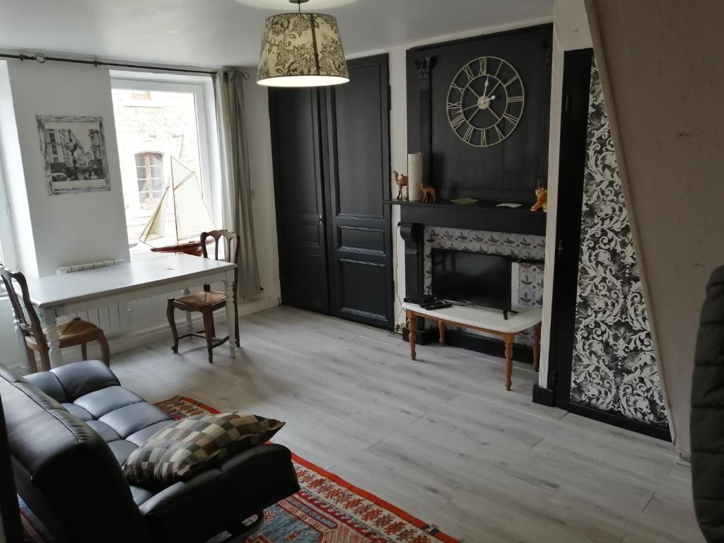 een woonkamer met een open haard en een klok aan de muur bij Les Fleurs Wimille / Wimereux in Wimille