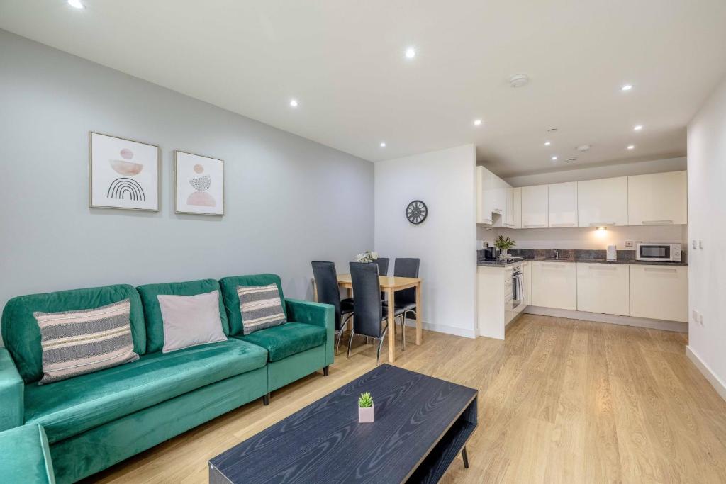 a living room with a green couch and a table at 2 BED AT SLOUGH STATION & PARKING - LONDON IN 20 MINS in Slough
