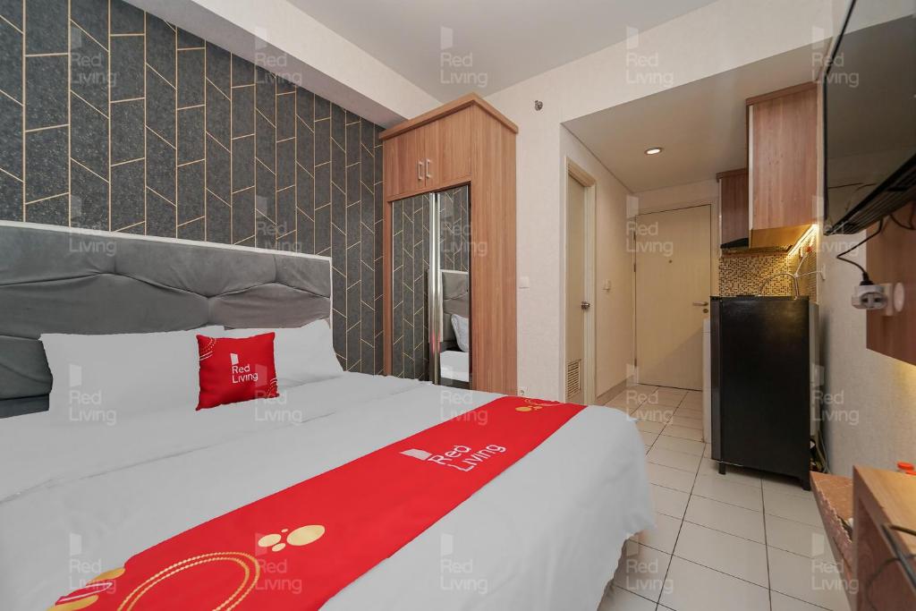 - une chambre avec un lit et une couverture rouge dans l'établissement RedLiving Apartemen Patra Land Urbano - Kamarku Tower Mid-West, à Bekasi