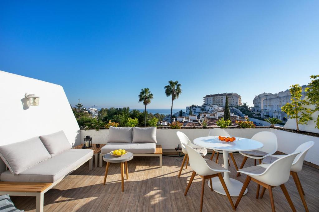 balkon z białymi meblami, stołem i krzesłami w obiekcie Torrequebrada terrace by Costarentals - Ref 76 w mieście Benalmádena