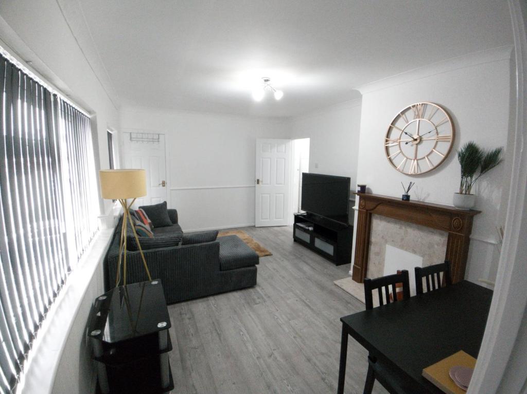 a living room with a couch and a clock on the wall at Exquisite Two Bed Apartment in Grays - Free Wi-Fi and Netflix in Stifford