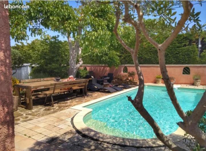 - une piscine dans une cour avec un banc en bois dans l'établissement Villa climatisée avec piscine, à Courthézon
