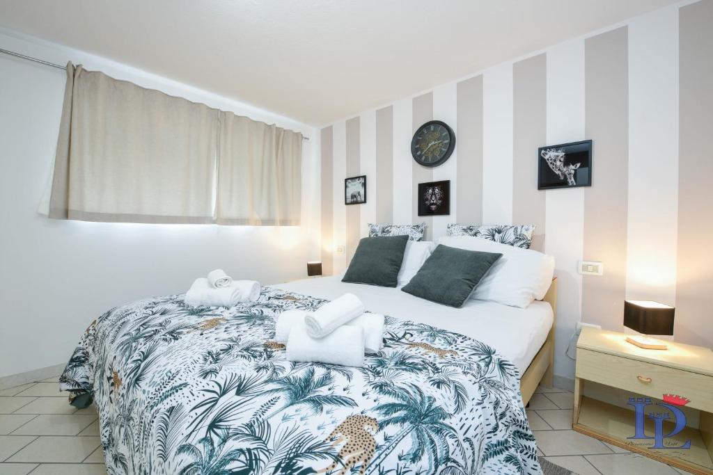 1 dormitorio con 1 cama grande y reloj en la pared en DesenzanoLoft Villa Palm Garda Beach, with garden, barbecue and pool, en Desenzano del Garda