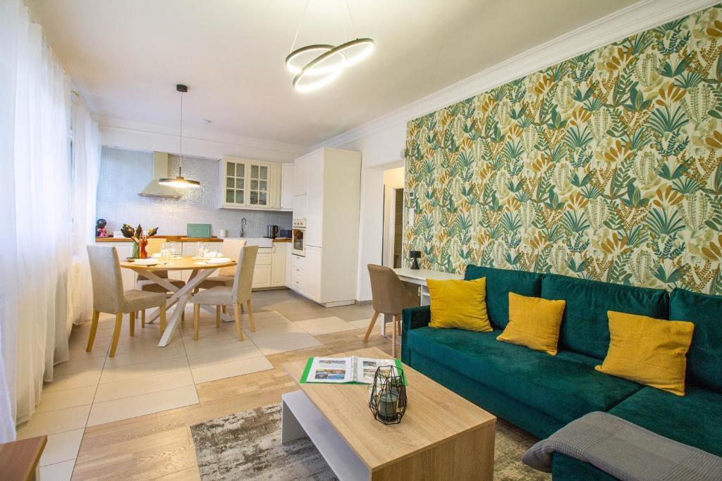 Hillside Lodge في بودابست: غرفة معيشة مع أريكة خضراء وغرفة طعام