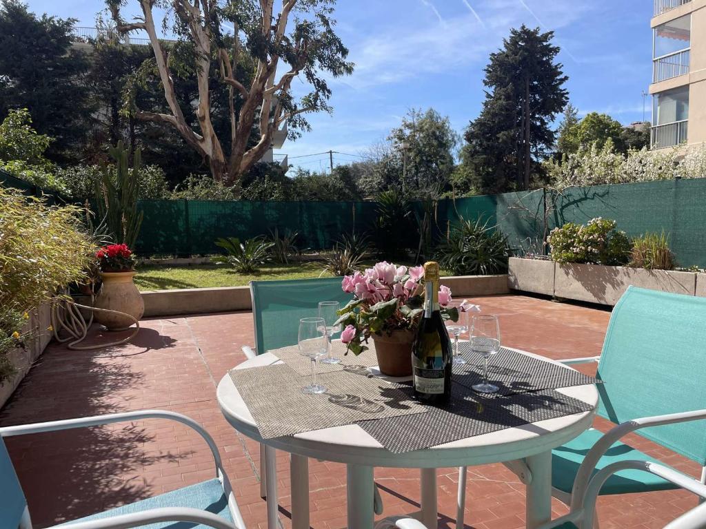 - une table avec une bouteille de vin et des fleurs sur la terrasse dans l'établissement Appartement avec Piscine & Tennis, Terrasse ensoleillée, Garage privé - Antibes - FR-1-252-126, à Antibes