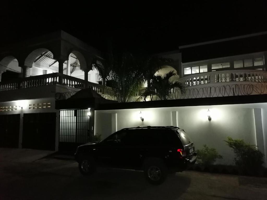 une voiture garée devant un bâtiment la nuit dans l'établissement Villa Eloy, à Lomé