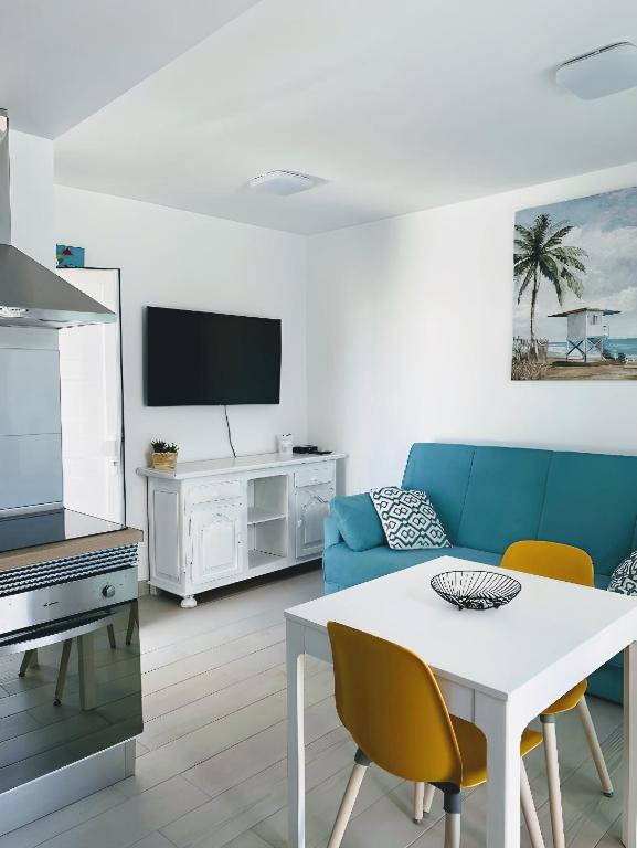 salon z niebieską kanapą i stołem w obiekcie Red Hibiscus Corralejo iRent Fuerteventura w Corralejo