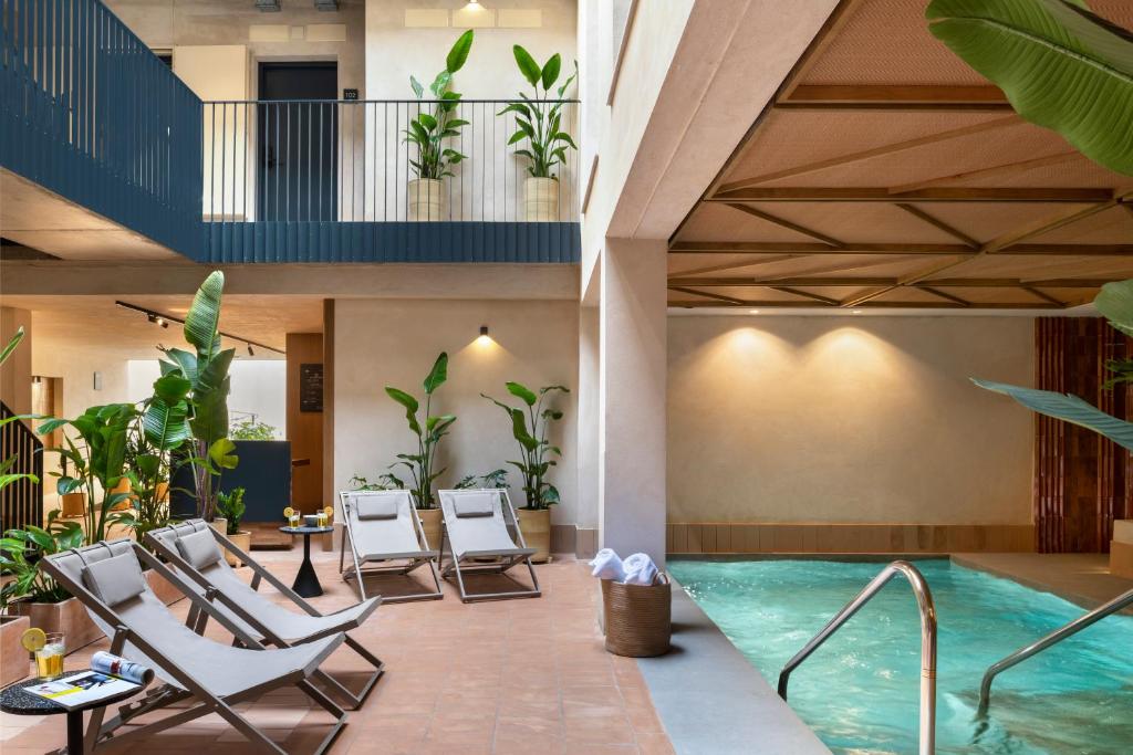 uma piscina num hotel com cadeiras e uma piscina em Magno Apartments Castilla em Sevilha