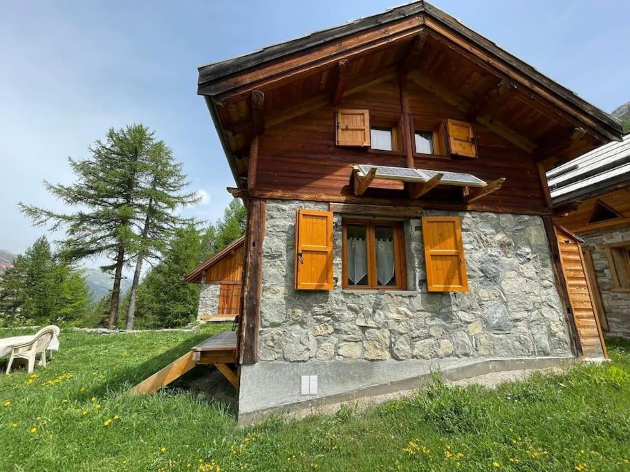 Blockhaus mit orangefarbenen Fensterläden und einer Bank in der Unterkunft Chalet d’alpage in Briançon