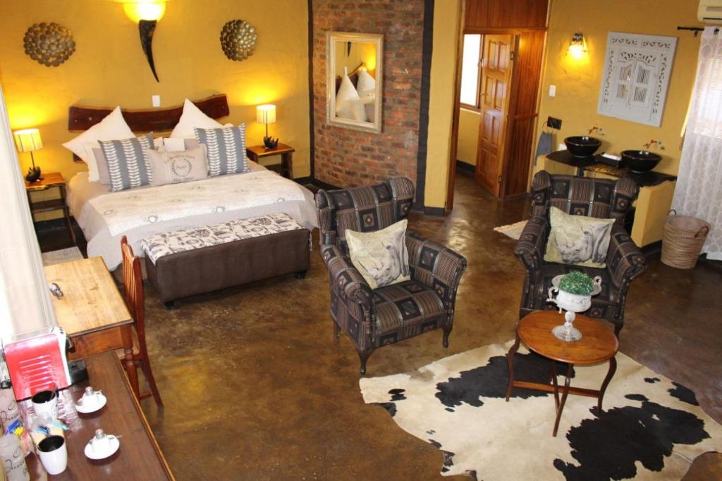 a bedroom with a bed and chairs in a room at Ndlovu Lodge in Pretoria