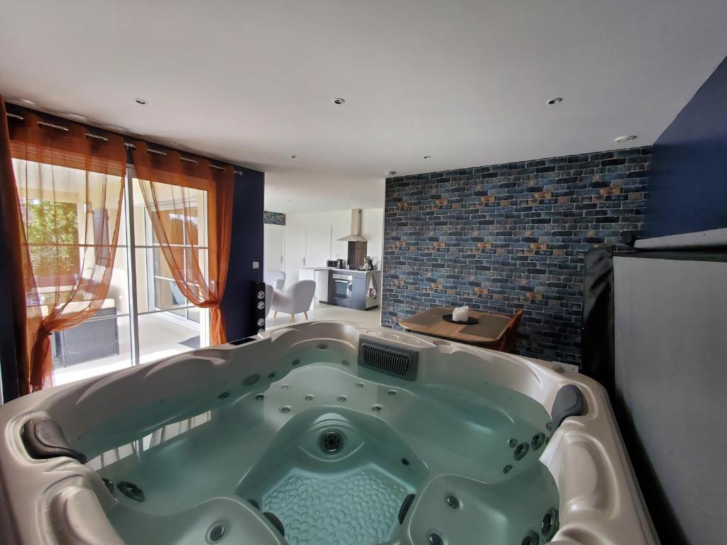 a large bath tub in a room with a kitchen at Hortensia, Gîte famille et amis in Fontenay-le-Comte