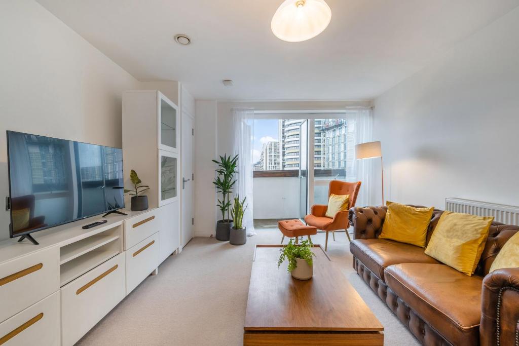 a living room with a couch and a tv at Luxury 2 Bedroom Large Balcony 5 Minutes to Kensington, Holland Park, Westfield Shopping Centre, Portobello Market in London