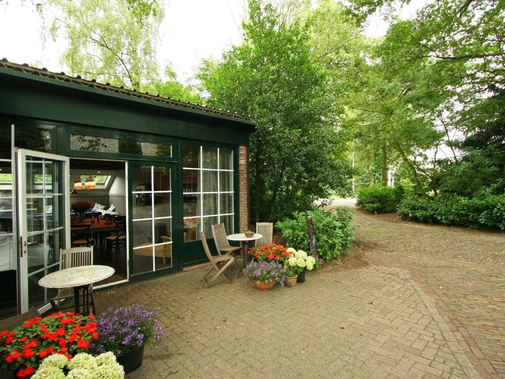 un patio con una mesa y flores frente a un edificio en Quietly located farmhouse with sauna and hot tub, en Balkbrug