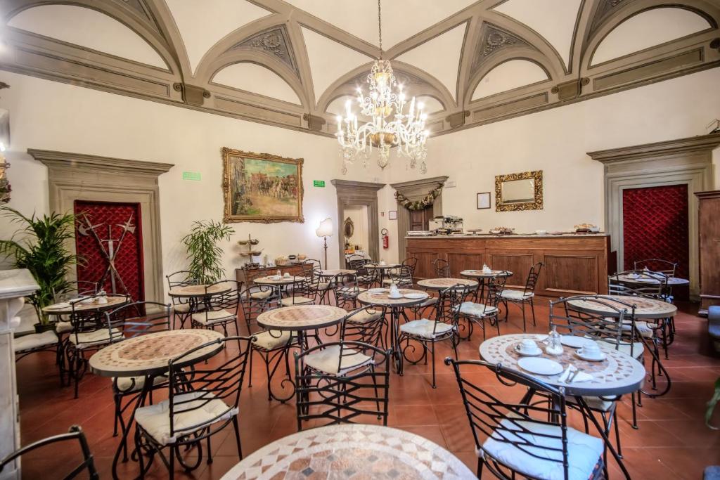 フィレンツェにあるマルテッリ ホテルのテーブルと椅子、シャンデリアが備わる広い客室です。