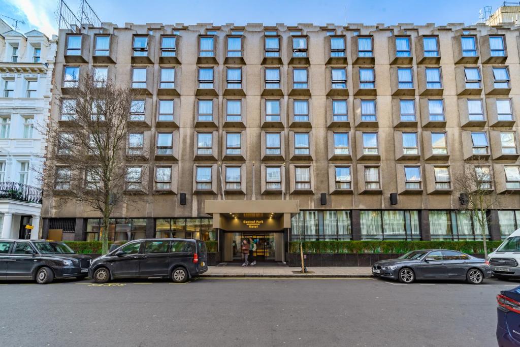 een gebouw waar auto's voor geparkeerd staan bij Central Park Hotel in Londen