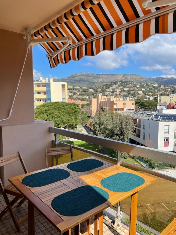 - un balcon avec une table, des chaises et un parasol dans l'établissement L’azur, au Lavandou