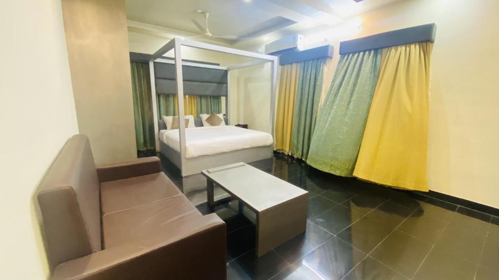 Habitación con cama, sofá y espejo. en Lotus-Explore Kerala 365 en Thiruvananthapuram