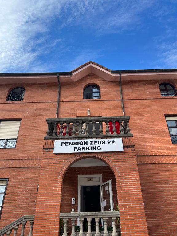 a red brick building with a sign on it at Pensión Zeus in Barakaldo