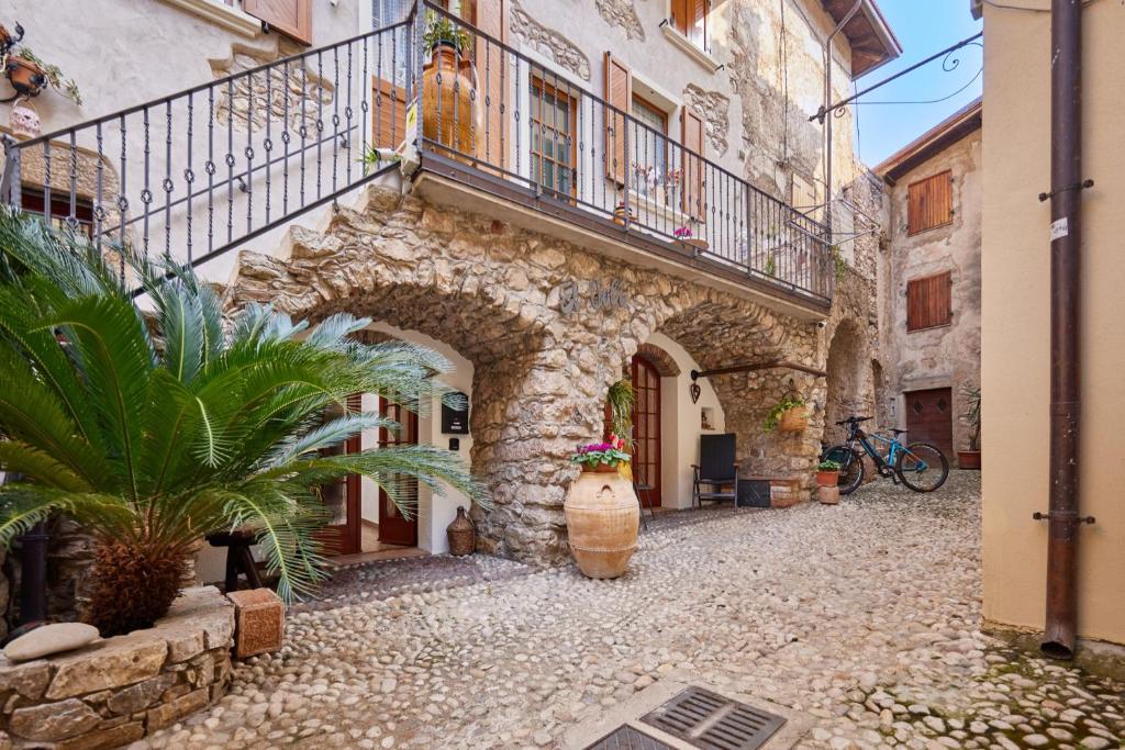 un callejón con un edificio de piedra con balcón y una planta en EL VOLT, en Malcesine