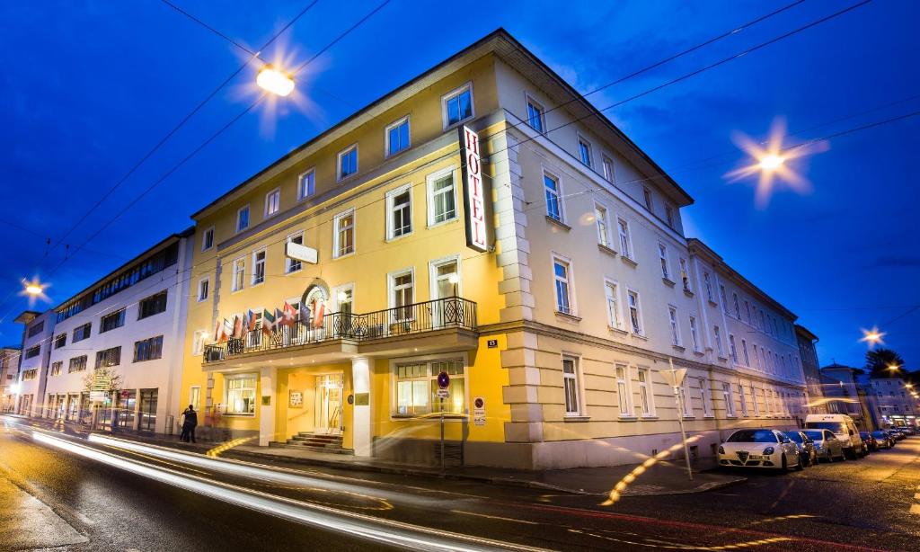 a large yellow building on a street at night at Theater Hotel Salzburg in Salzburg